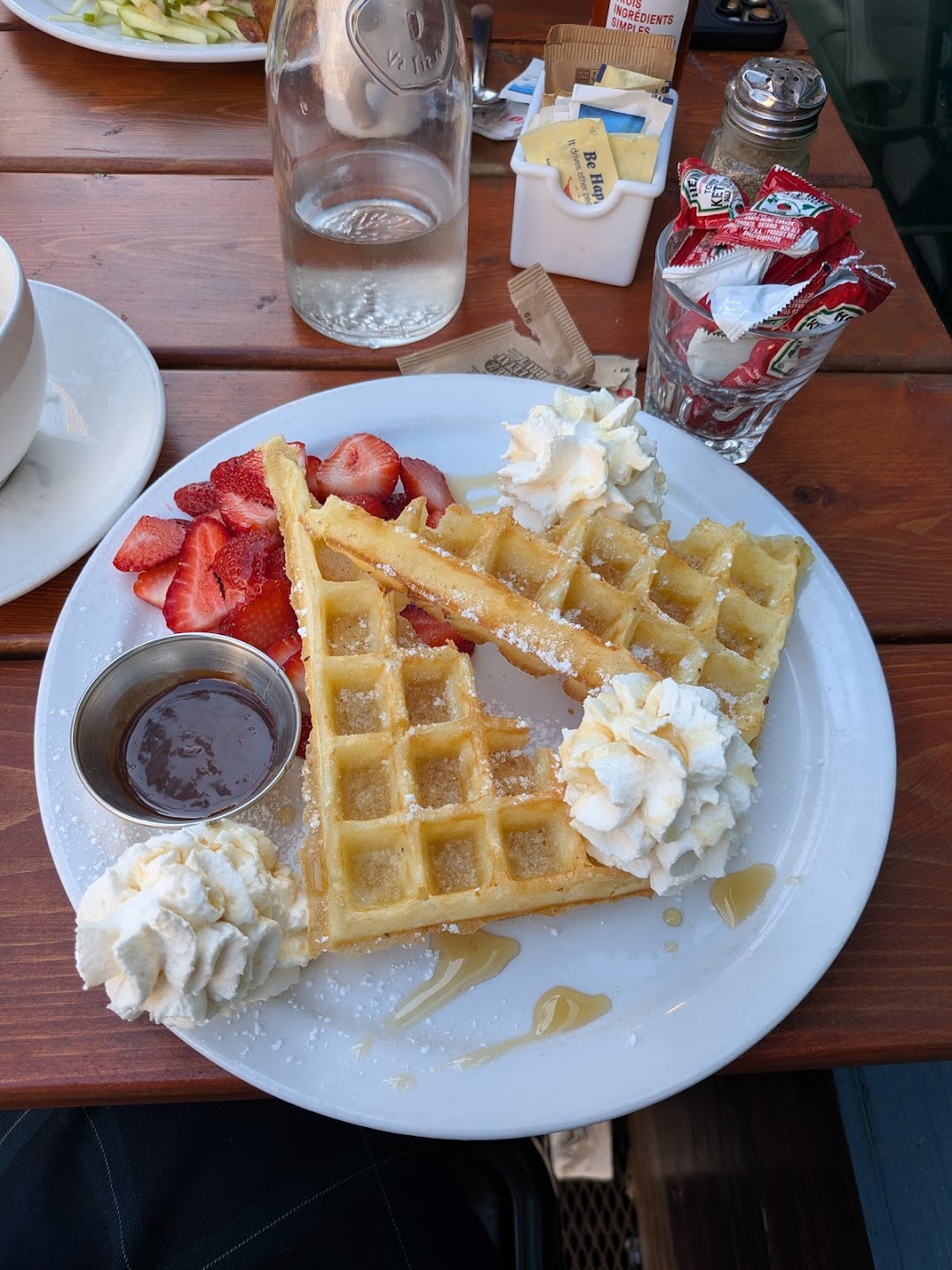 Waffles with fresh strawberries, whipped cream, and powdered sugar at Petit Dejeuner