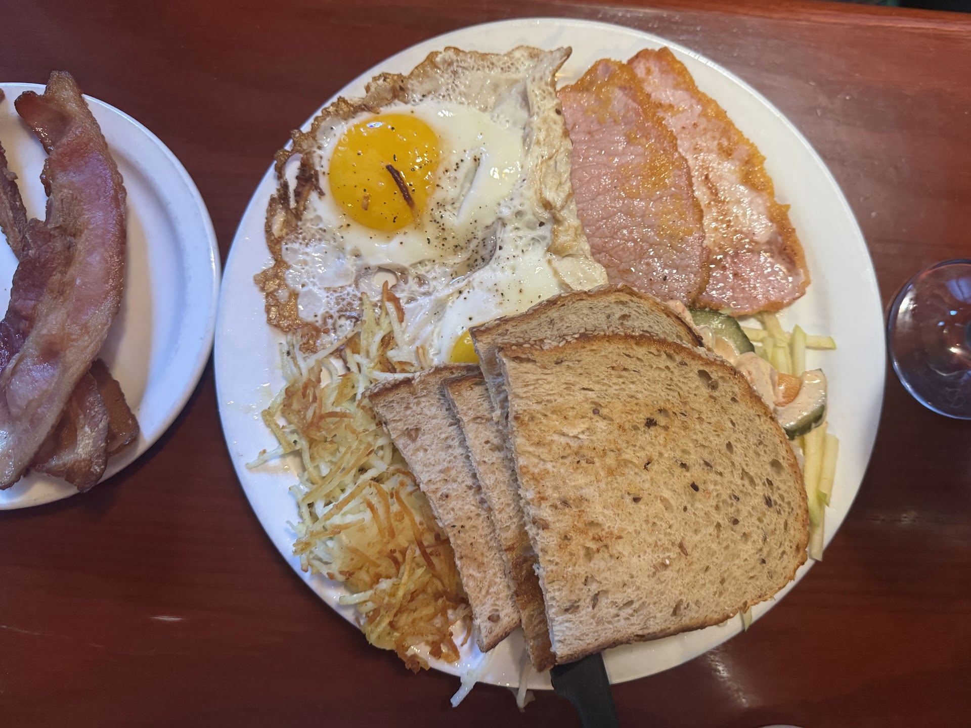Classic breakfast plate with eggs, ham, toast, and hash browns
